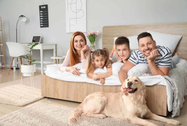 Happy family posing together on a large bed with a dog
