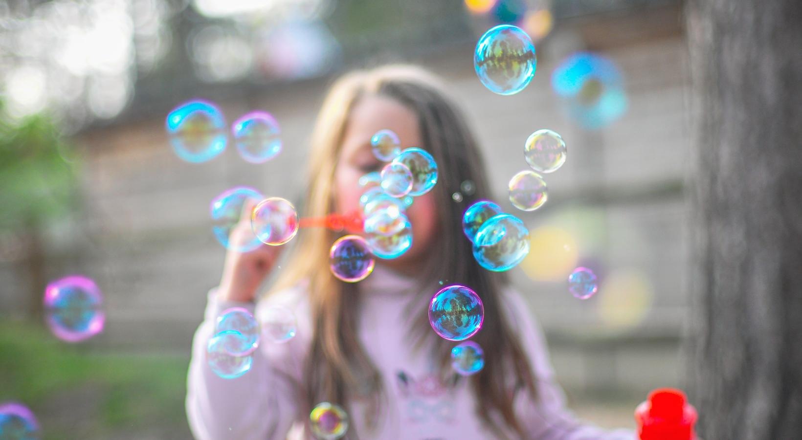 Young girl blowing bubbles with a bubble wand