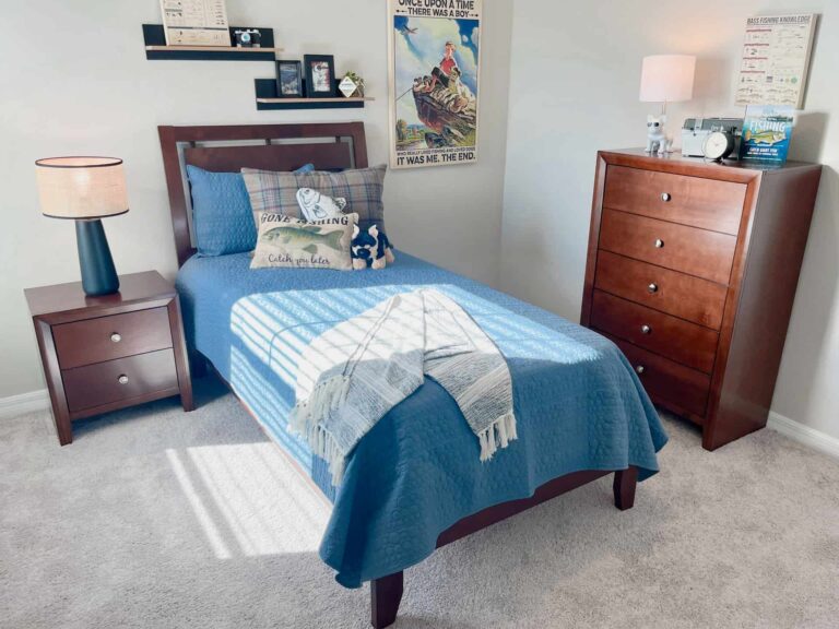 Single bedroom with twin-size bed, nightstand with lamp and drawers, dresser, and floating shelves