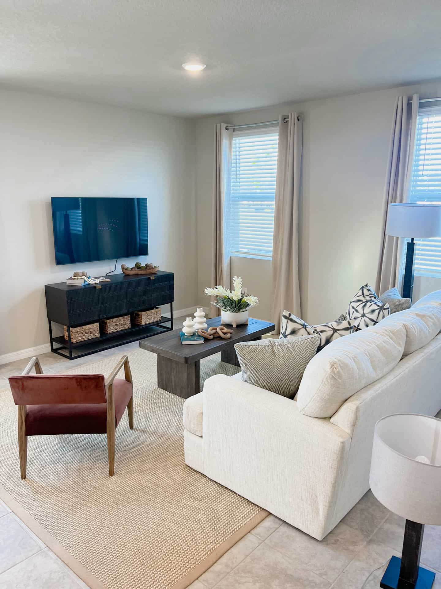 Townhome living room with sofa, armchair, coffee table, lamp, and wall-mounted TV