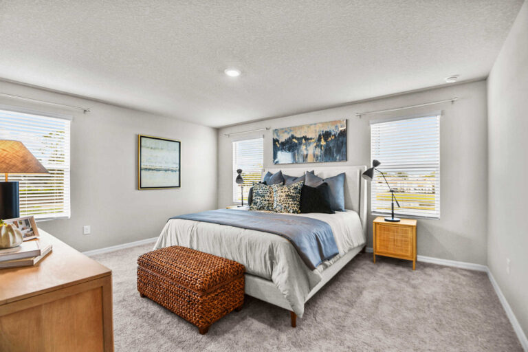 Master bedroom with dresser, foot-of-bed basket ottoman, and twin nightstands with reading lamps