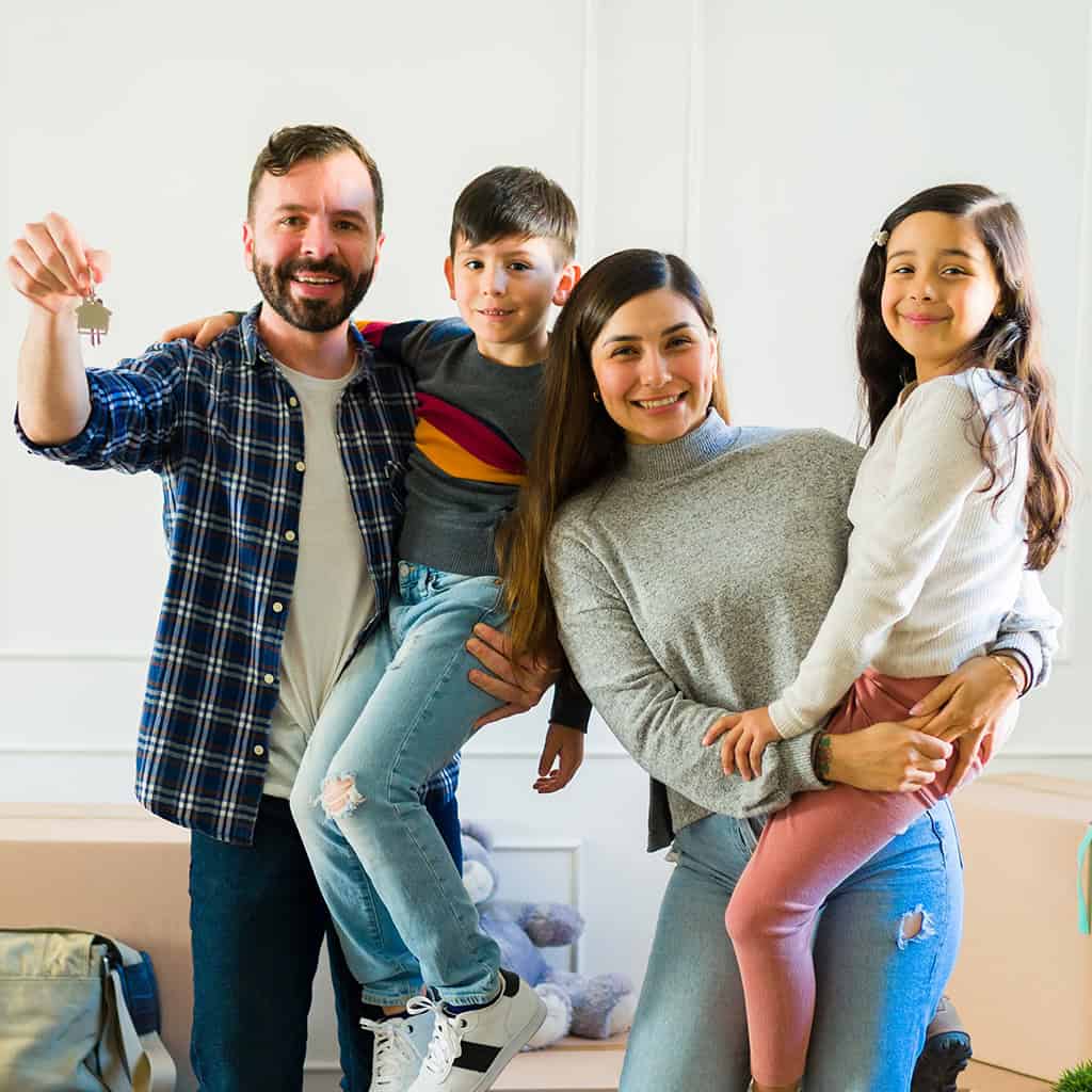 Family with young kids move into their new home as father holds up the keys